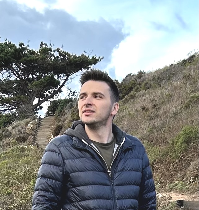 A photo of a very handsome young man looking far away, hills of California on the background